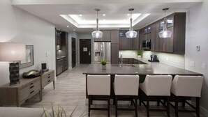 A modern kitchen with a central island, pendant lighting, and stainless steel appliances.