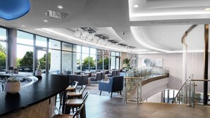 A modern interior with a curved bar, seating area, and large windows offering views of the city.