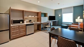 Una cocina moderna equipada con refrigerador, microondas y lavavajillas. Cuenta con una zona de comedor con mesa y sillas, y un televisor en una esquina.