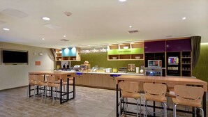 Un área de cocina moderna con barra, taburetes y diversos electrodomésticos.
