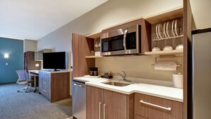 Una cocina moderna con armarios de madera, un microondas de acero inoxidable y un lavavajillas integrado.