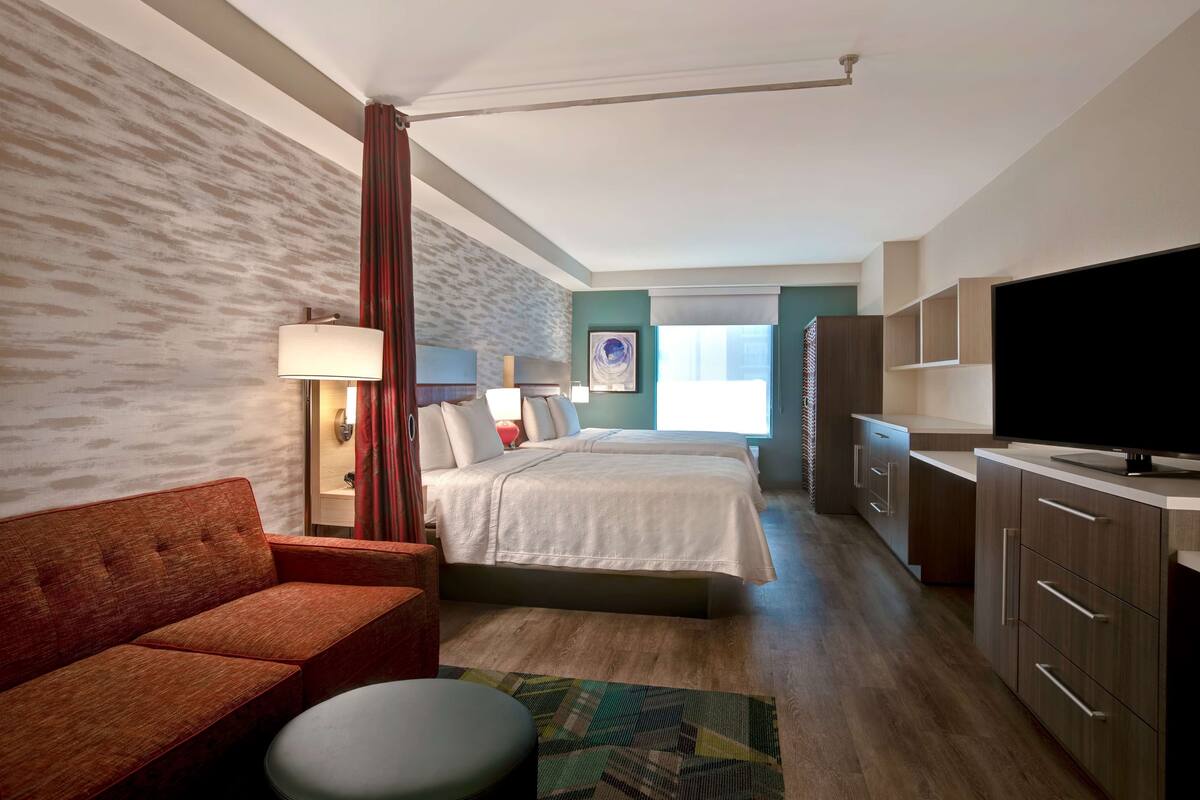 Ein Hotelzimmer mit Bett, einer Couch, einem Fernseher und einem Schreibtisch.