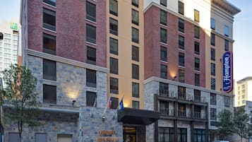 Un hotel con fachada de piedra, varios balcones y un cartel de Hampton Home 2 Suites by Hilton.