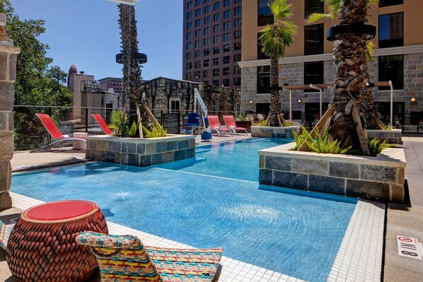 Una piscina con sillones de descanso y palmeras.
