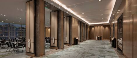 A spacious hotel lobby with a high ceiling, recessed lighting, and a patterned carpet.