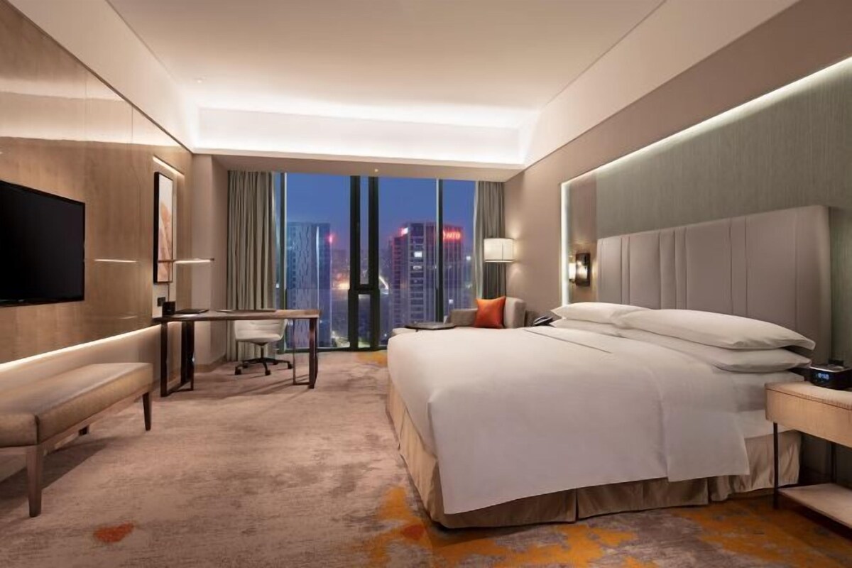 Una habitación de hotel con cama, escritorio y televisor.
