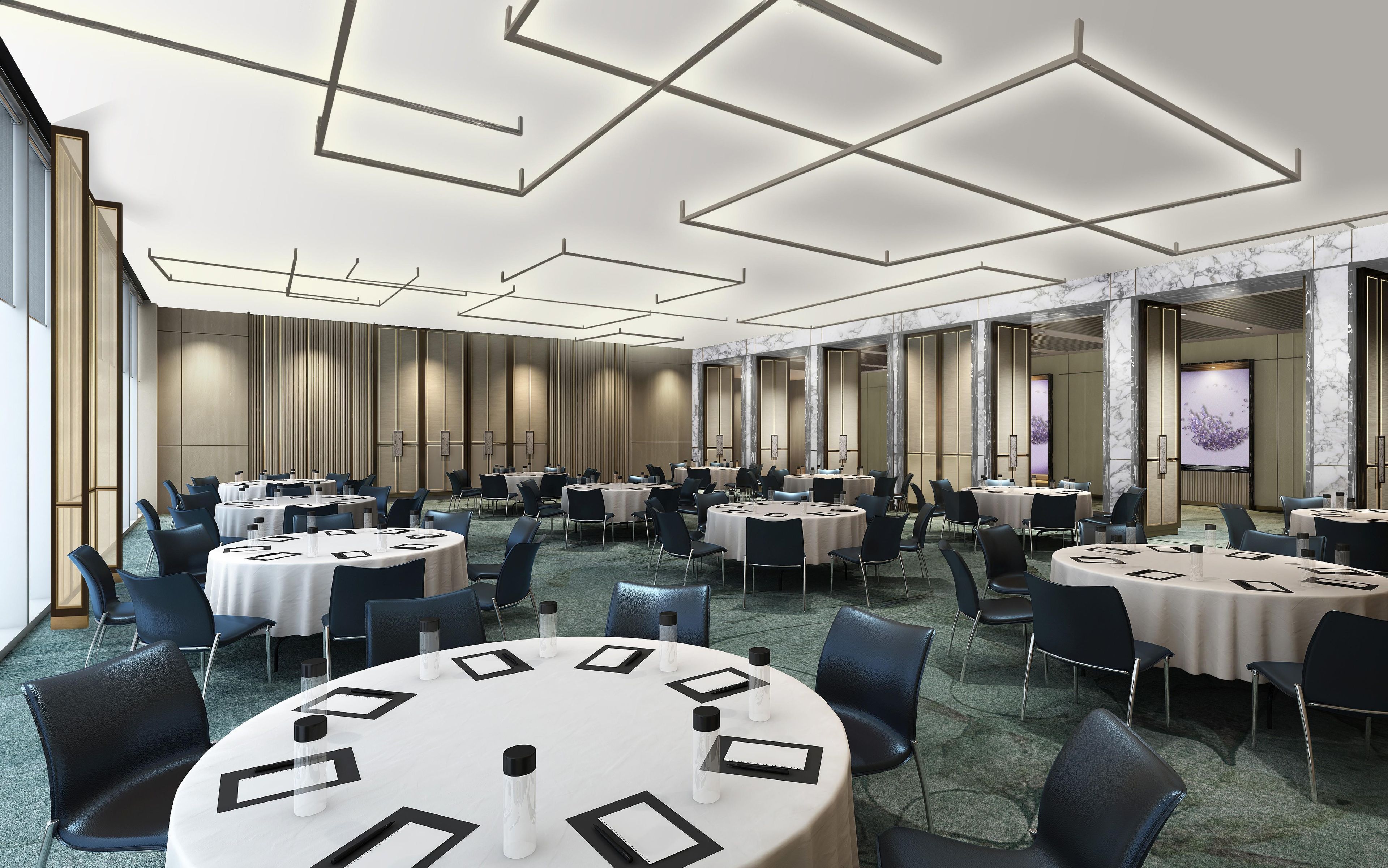 A conference room with multiple tables and chairs, a marble wall, and a large screen.