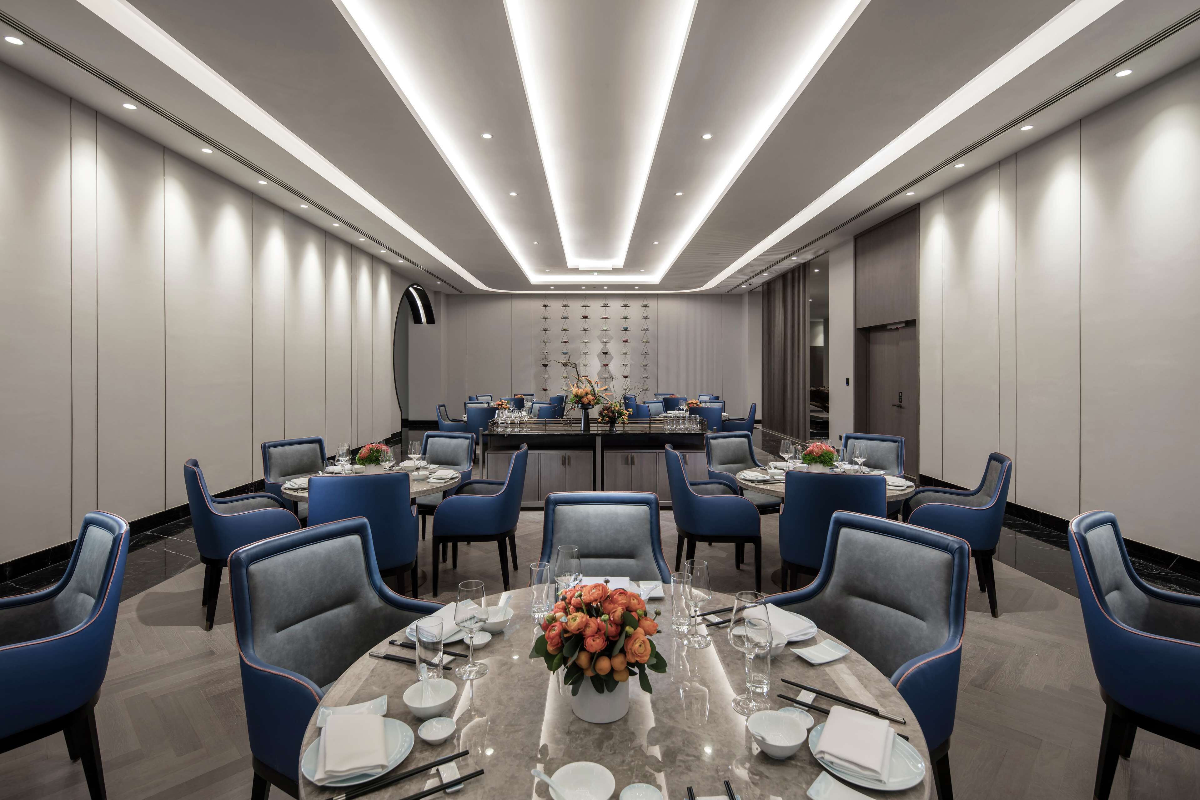 A modern conference room with round tables, blue chairs, and a central floral arrangement.
