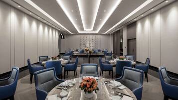 A modern conference room with round tables, blue chairs, and a central floral arrangement.