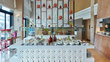Un hall d’hôtel moderne avec un buffet central proposant une variété de plats et agrémenté de vases décoratifs.