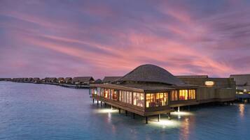 A waterfront resort with overwater bungalows connected by a wooden walkway.