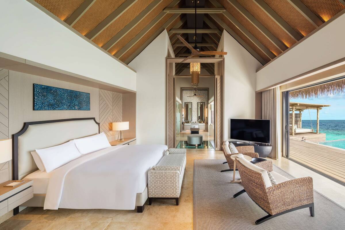 A spacious bedroom with a large bed, a TV, and a view of the ocean.
