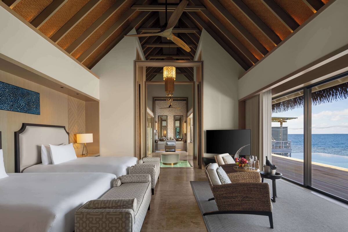 A hotel room with a large bed, a sofa, a TV, and a view of the ocean.
