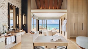 A spacious bathroom with a large bathtub, a vanity with a mirror, and a view of the ocean.