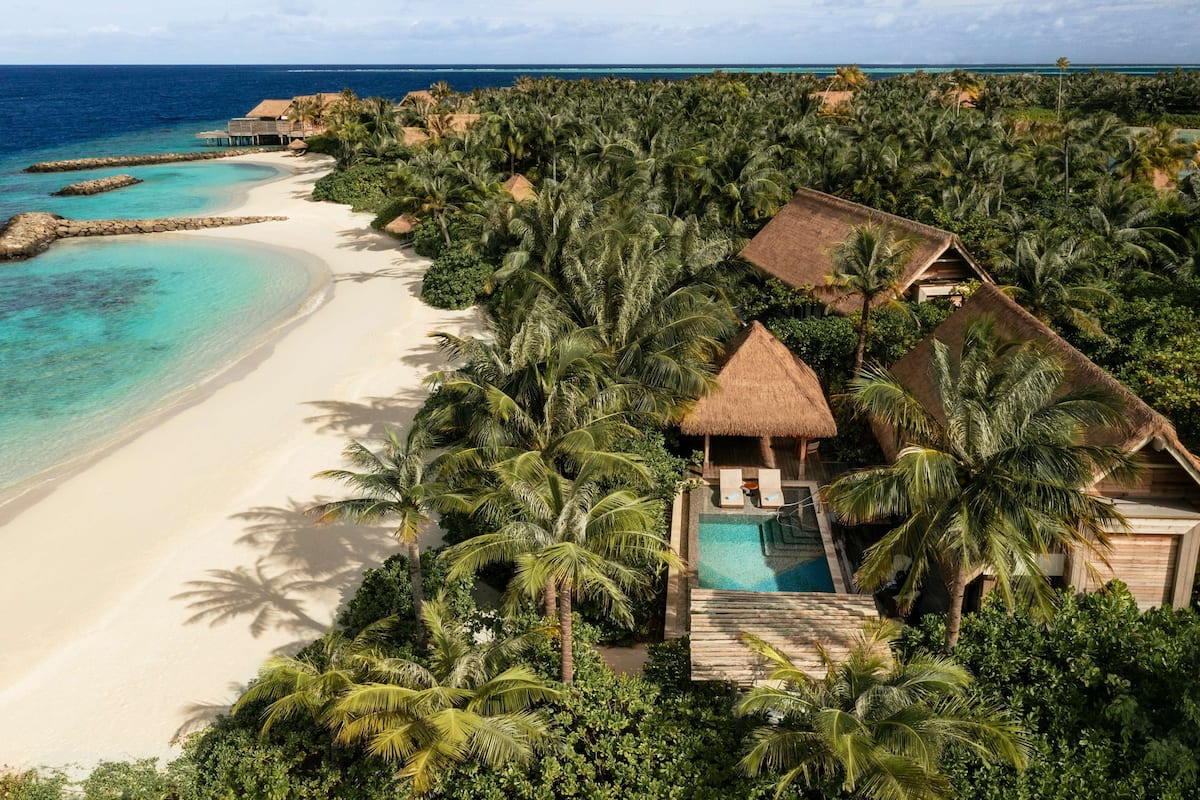 A tropical resort with a private pool, beachfront, and thatched-roof structures.