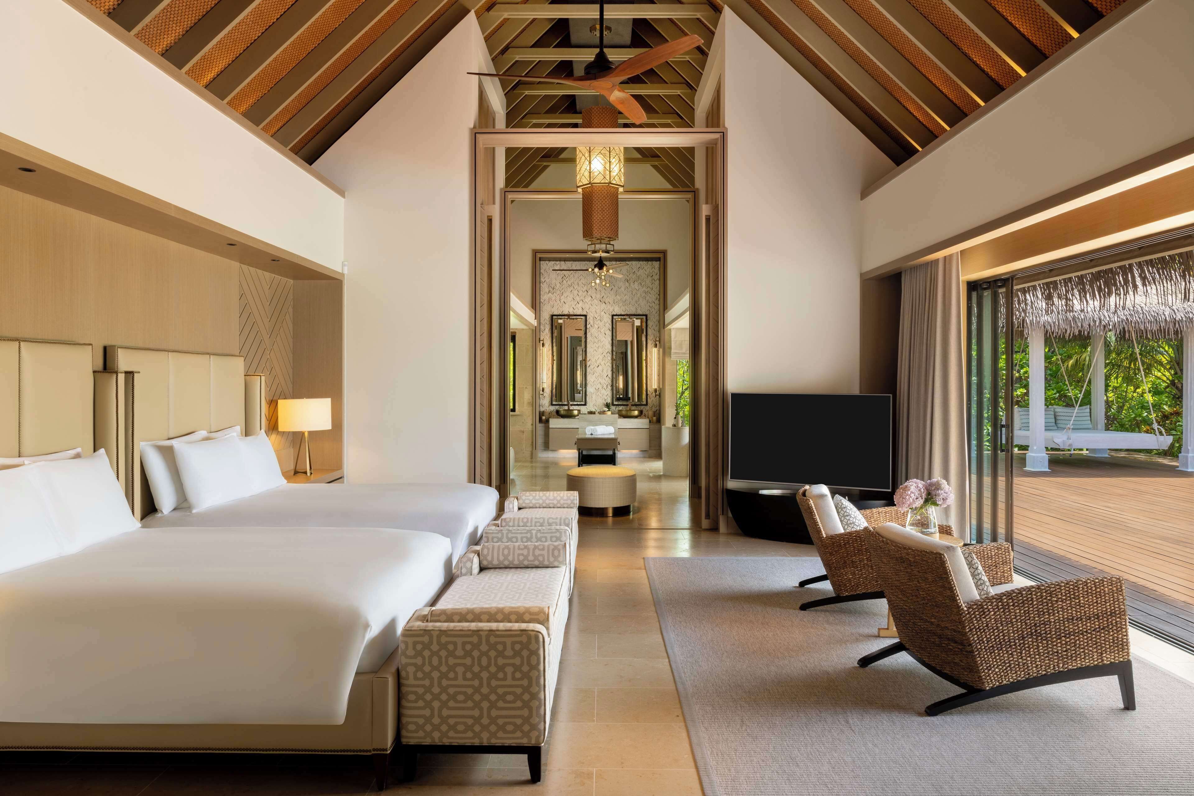 Una habitación de hotel moderna con una cama grande, dos sofás, un televisor y vistas al exterior.
