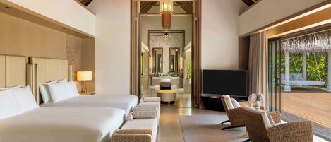 Una habitación de hotel moderna con una cama grande, dos sofás, un televisor y vistas al exterior.