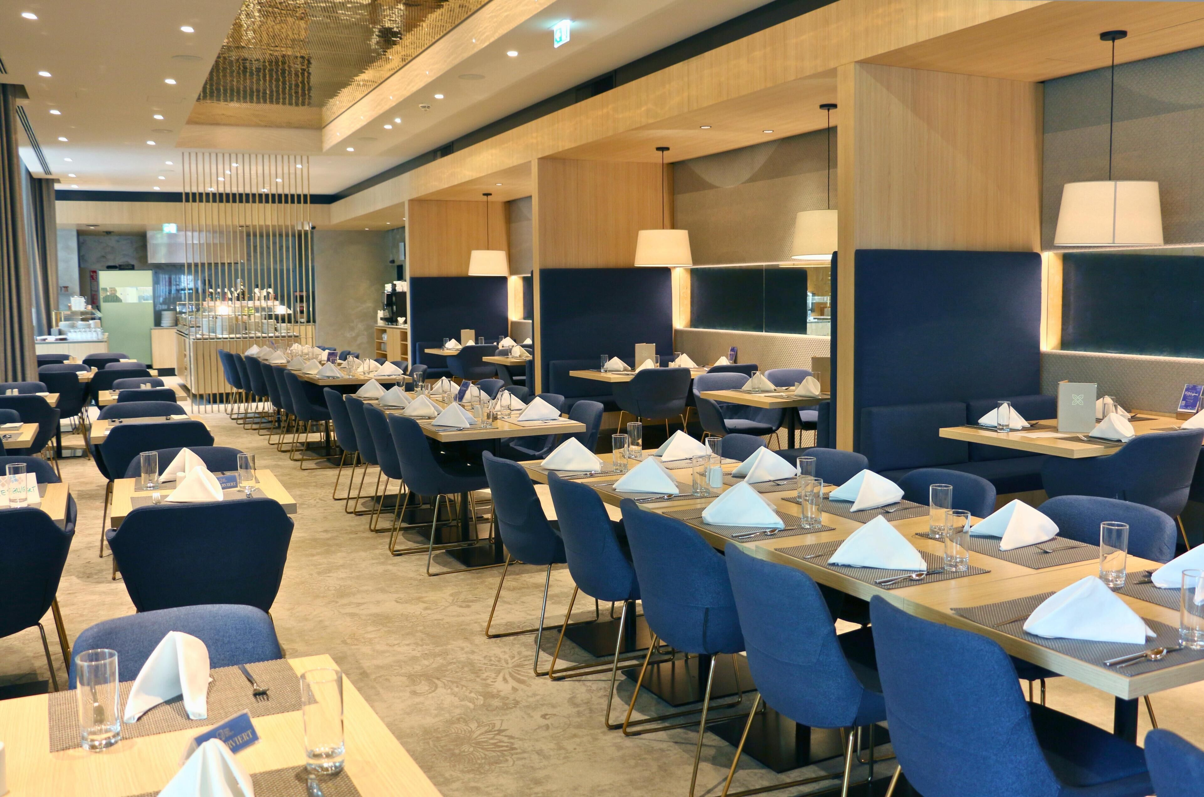 Zona de dinar d'hotel amb diverses taules preparades per als clients, cada una amb un lloc assegut.