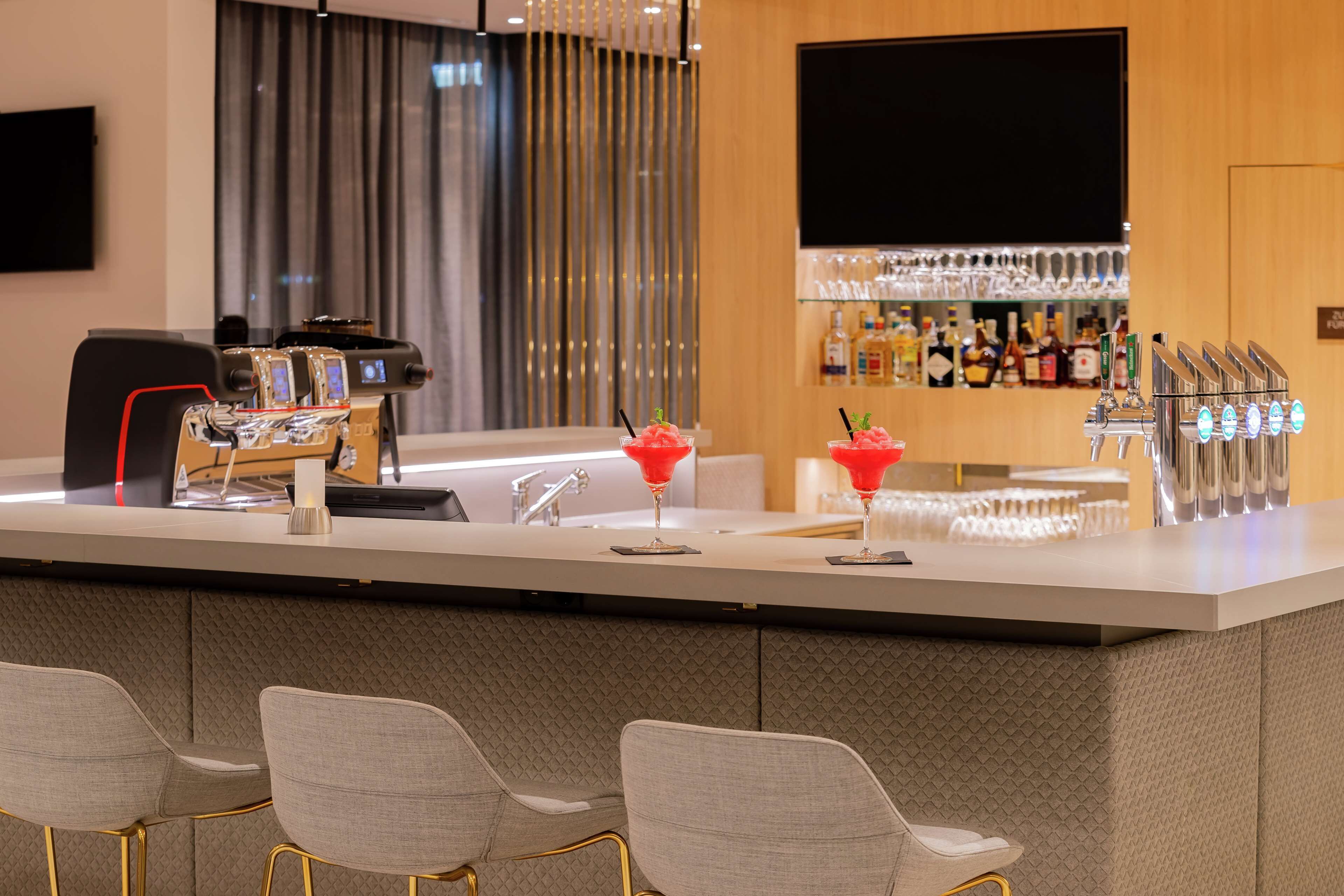 A modern bar area with a bar counter, multiple taps, and two stools.