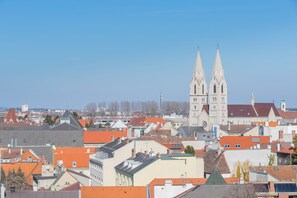 A cityscape with a prominent church featuring twin spires, surrounded by various buildings with red and grey roofs. - Hilton Garden Inn Wiener Neustadt (Wiener Neustadt)