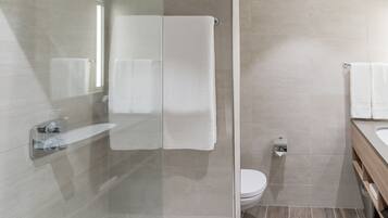A modern bathroom with a glass shower enclosure, a toilet, and a vanity with a mirror.