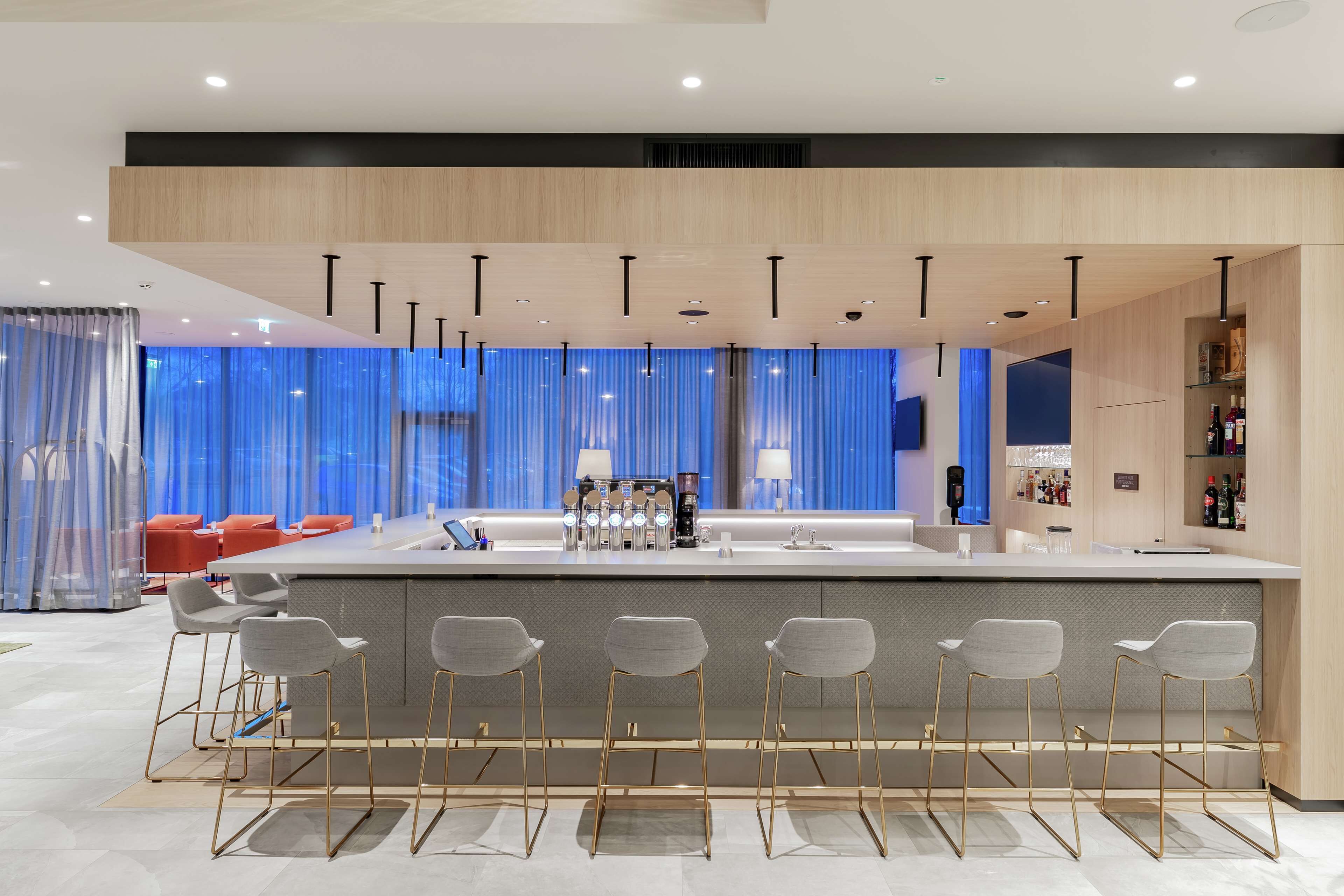 Una cocina moderna con una isla central, taburetes de bar y vistas a la ciudad a través de amplias ventanas.