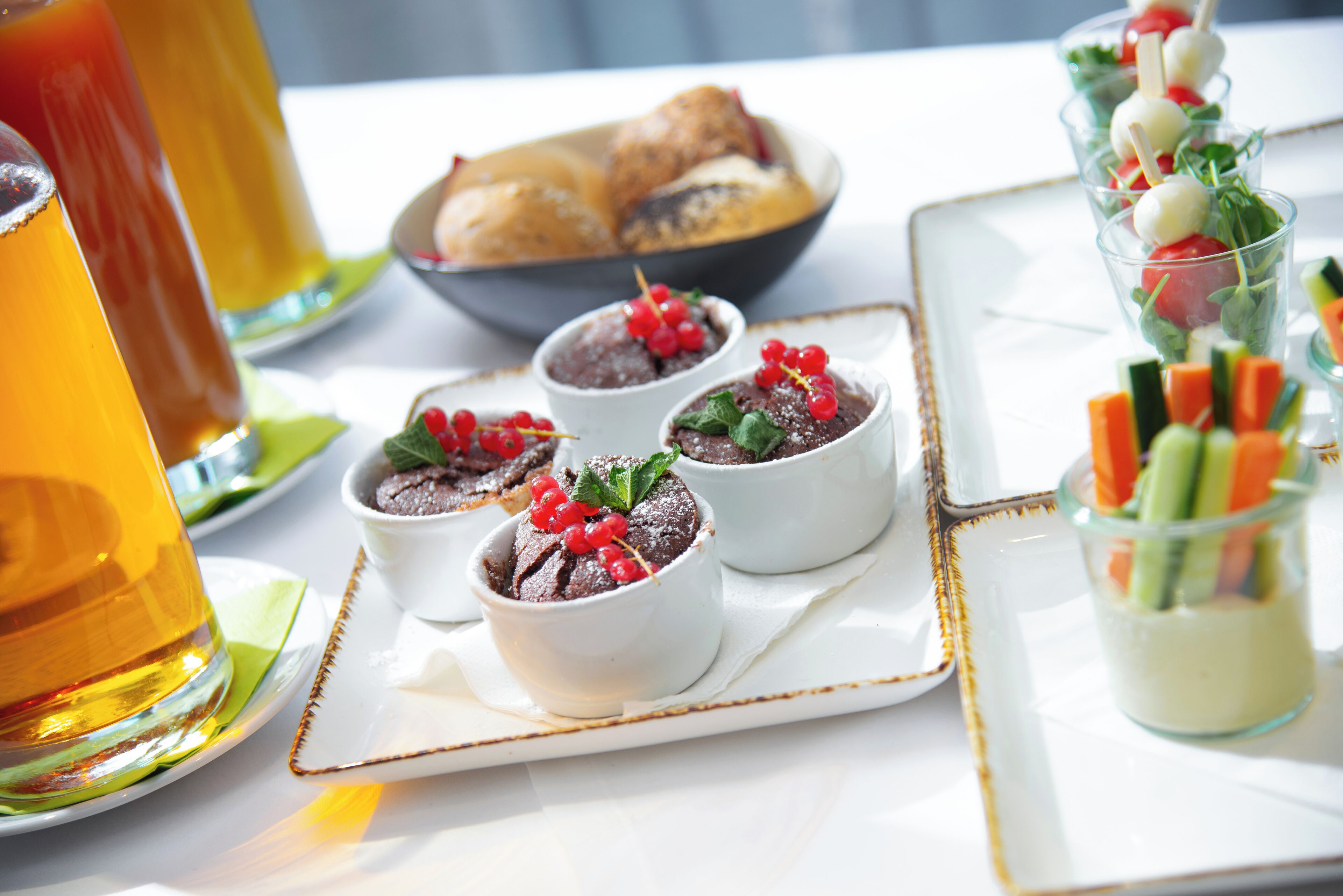 A table with dessert cups, a beverage, and a dish of pastries.