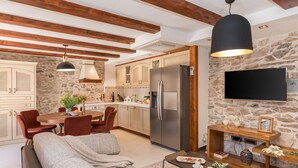 Une cuisine moderne avec des murs en pierre, des poutres en bois et un grand réfrigérateur.