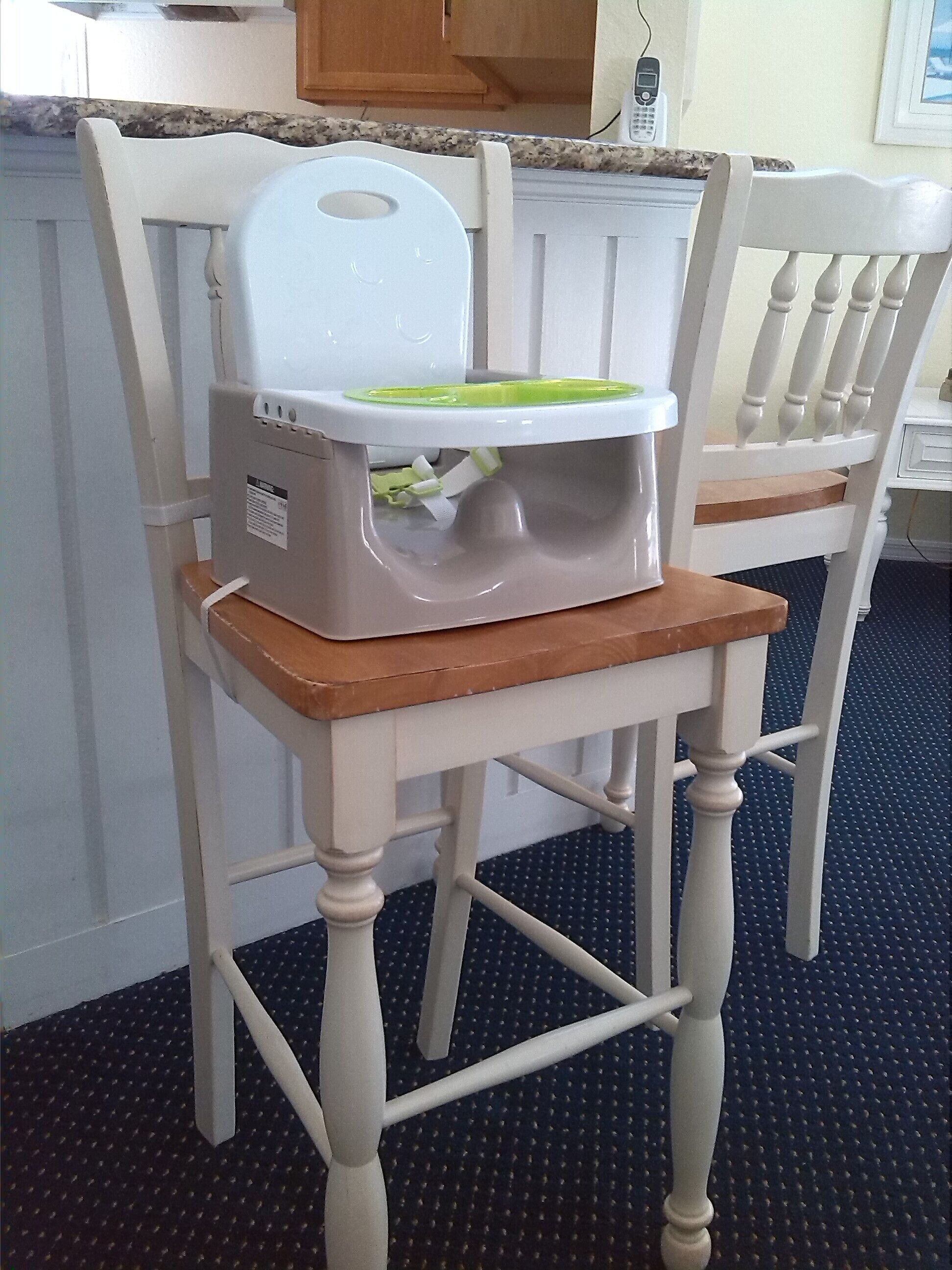 A kitchen with a white countertop, a white chair with a wooden seat, and a white radiator.