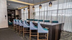 A modern conference room with a long table, teal upholstered chairs, and pendant lighting. - Hampton Inn & Suites by Hilton Puebla (San Andrés Cholula)