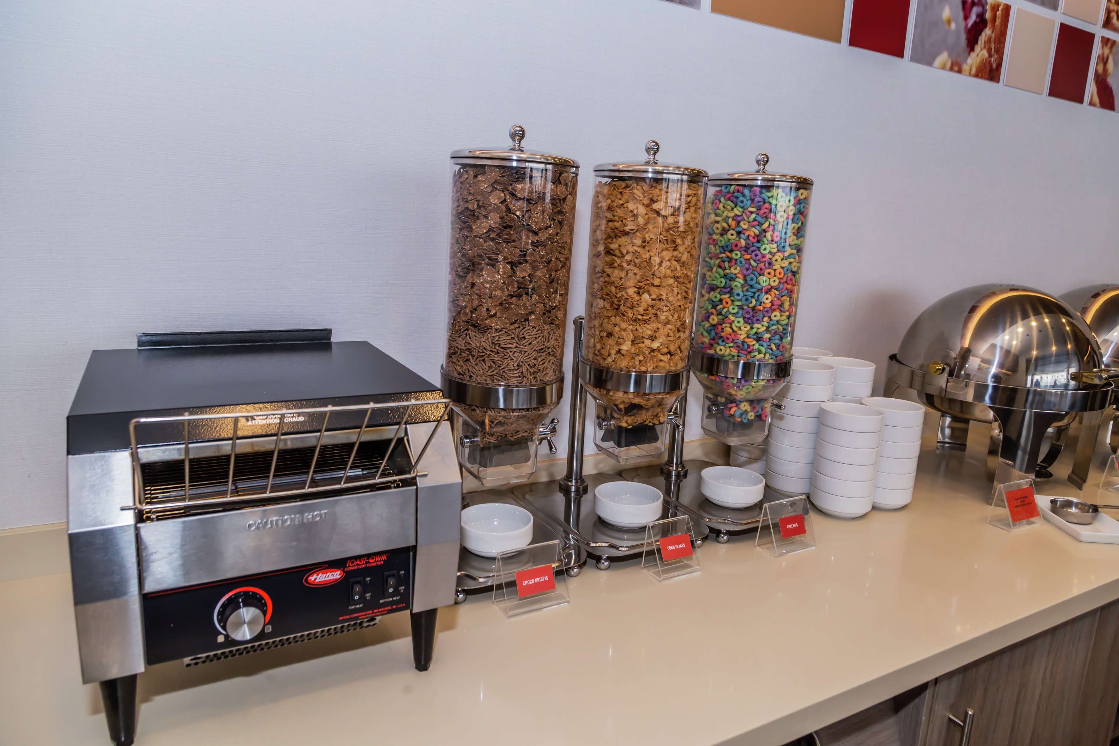 A self-service food station with a steam oven, cereal dispensers, and bowls for serving.