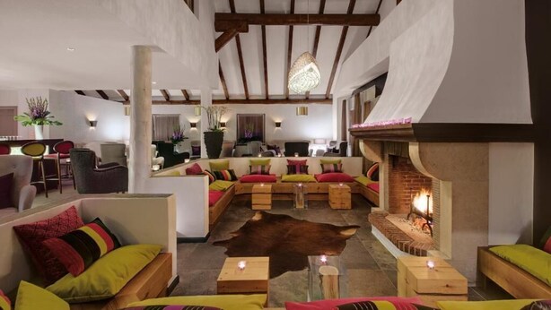 Un área de descanso acogedora con chimenea, muebles de madera y un tapete de cuero.