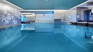 Una amplia piscina interior de diseño moderno, con un panel de control y una zona de estar con vistas a la piscina.