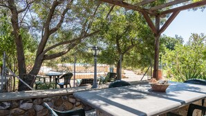 Eine Terrasse im Freien mit Steinmauern, einem Tisch, Stühlen und einer Pergola.