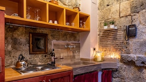 Een keuken met houten kasten, een stenen muur en een inbouwkast met glazen servies.