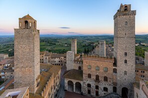 A historic stone building with two prominent towers and a central courtyard. - Medieval Tower experience with Panoramic Rooftop, San Gimignano (Italia)