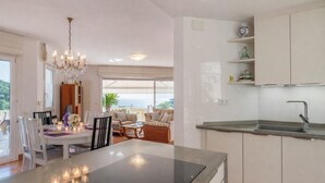 A modern kitchen with a central island, white cabinetry, and a view of the sea.