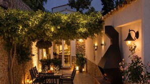 An outdoor patio with stone walls, a table with chairs, and a grill.