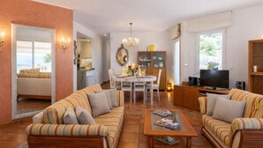 A spacious living room with striped sofas, a dining table, and a TV.