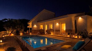A modern house with a swimming pool, outdoor seating, and warm lighting.