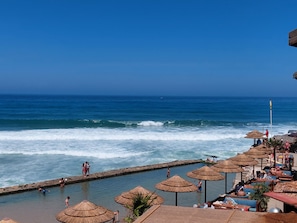 A coastal resort with a swimming pool, beach umbrellas, and ocean views. - Atlantic view house/front of the sea, private pool, Azenhas do Mar beach by walk (Colares)