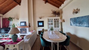A living room with a fireplace, a television, a dining table with chairs, and a painting on the wall. - Atlantic view house/front of the sea, private pool, Azenhas do Mar beach by walk (Colares)