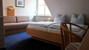 Una camera da letto con un letto, una sedia di legno, un divano, un tavolino e un quadro appeso al muro.