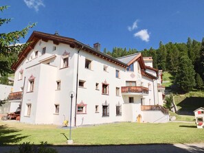 A multi-story building with a white facade, multiple balconies, and a well-maintained lawn.