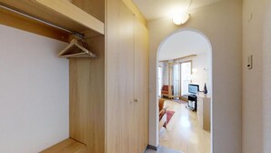 Un corridoio con un armadio in legno, uno specchio e una porta che dà su un soggiorno con televisore e divano.