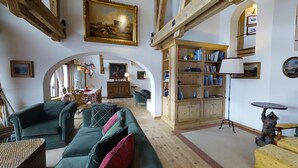 Ein gemütliches Wohnzimmer mit einem grünen Sofa, einer Holzbibliothek und einem Essbereich mit Tisch und Stühlen.