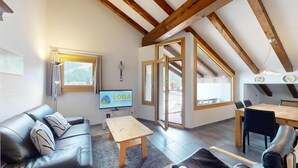 Una sala de estar moderna con un sofá de cuero, una mesa de madera y un televisor que muestra 'LOGA'.