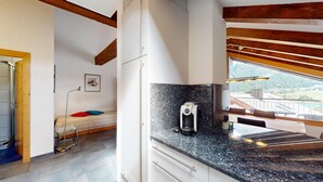 Una cocina moderna con encimera de granito, cafetera y vistas a un balcón con paisaje panorámico.