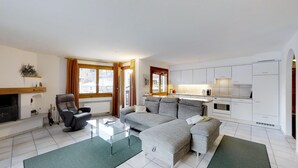 A modern living room with a sofa, a glass coffee table, and a fireplace. - Spacious 3½-room apartment on the second floor, ca. (Silvaplana)