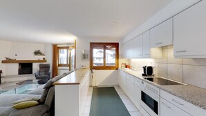 A compact kitchen with white cabinets, a built-in oven, and a coffee machine. - Spacious 3½-room apartment on the second floor, ca. (Silvaplana)